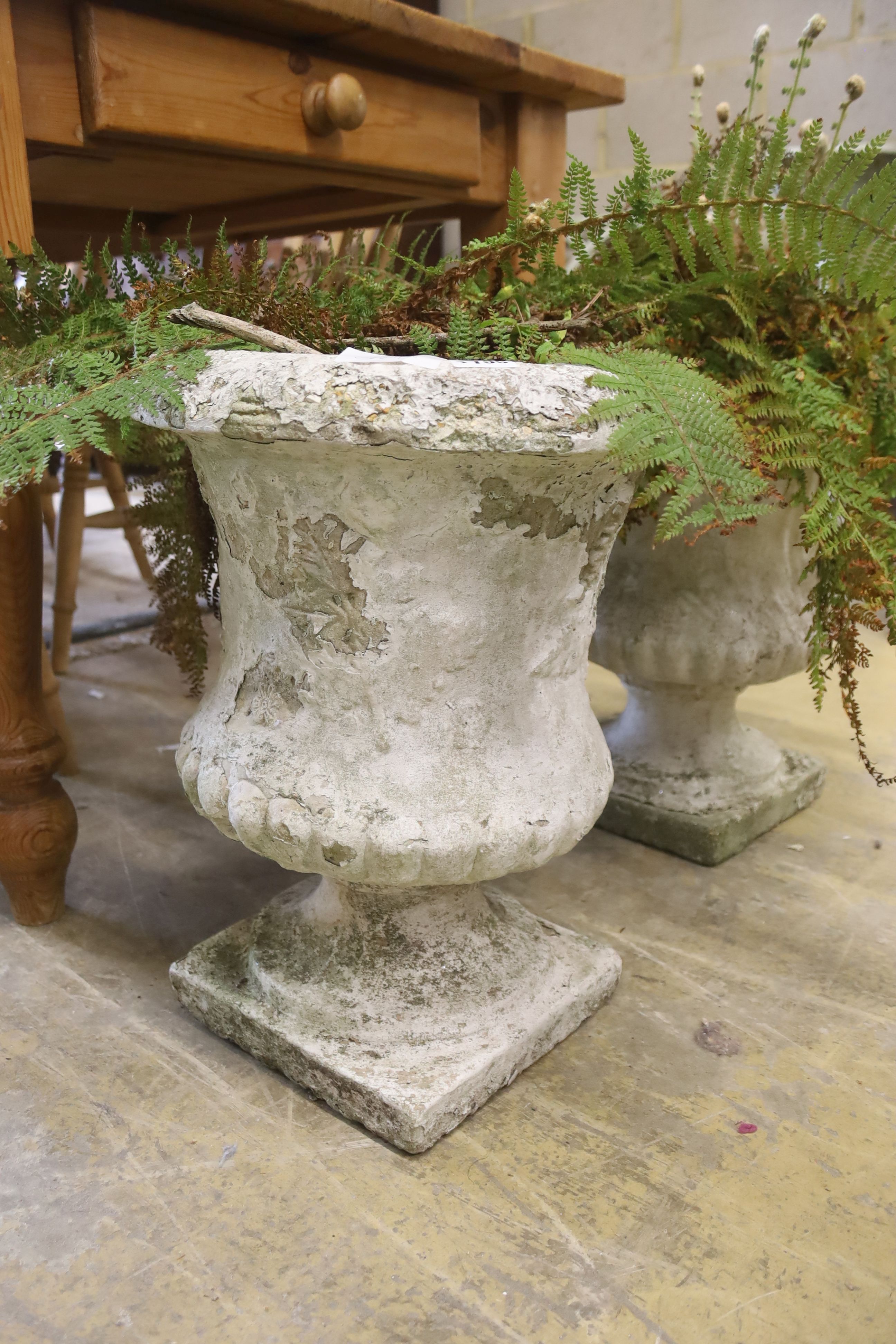 A pair of reconstituted stone campana garden urns on stands, diameter 36cm, height 45cm